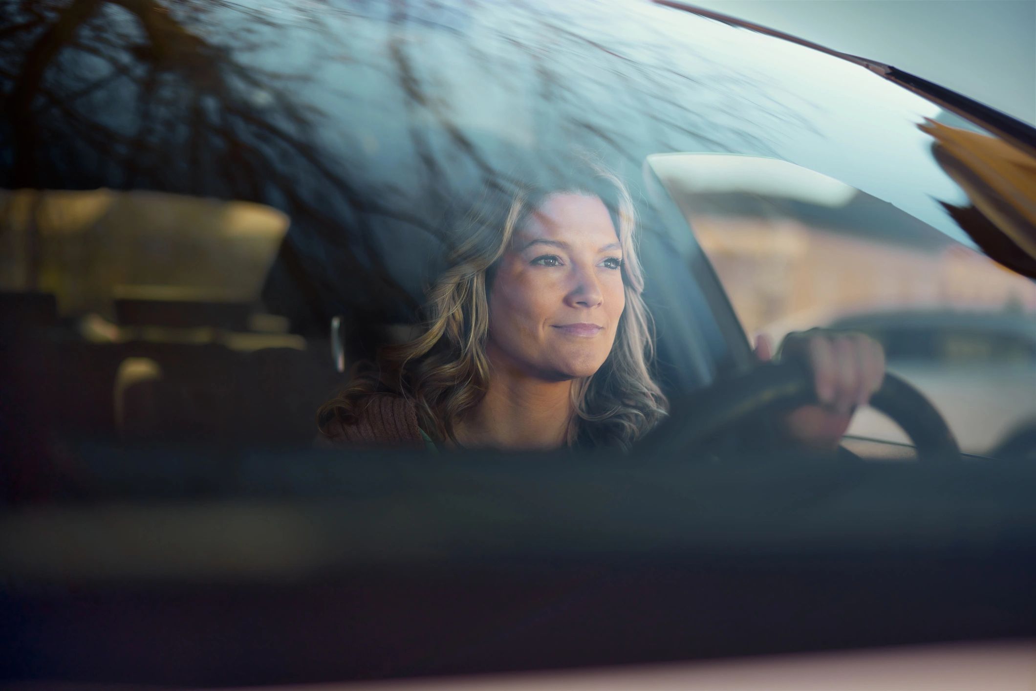 Smiling woman going on a road trip by car.