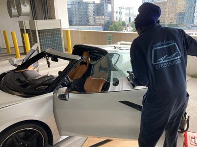 A technician at Juste's Glass completing a windshield replacement auto glass job on a Corvette in Atlanta, GA
